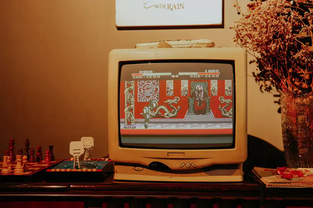 A glowing CRT television displaying a retro game next to an opened game console motherboard